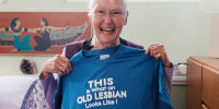 Edie Daly holds a blue t-shirt that says "This is what an old lesbian looks like!"